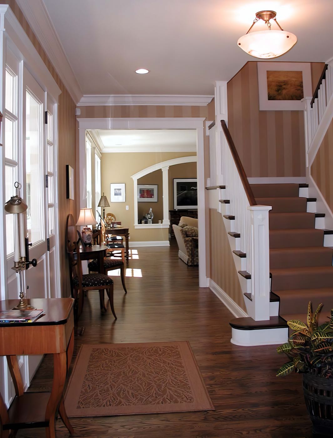 Entrance hall with a painted stair, white balusters, striped walls and a dark timber floor running through to the rooms beyond.