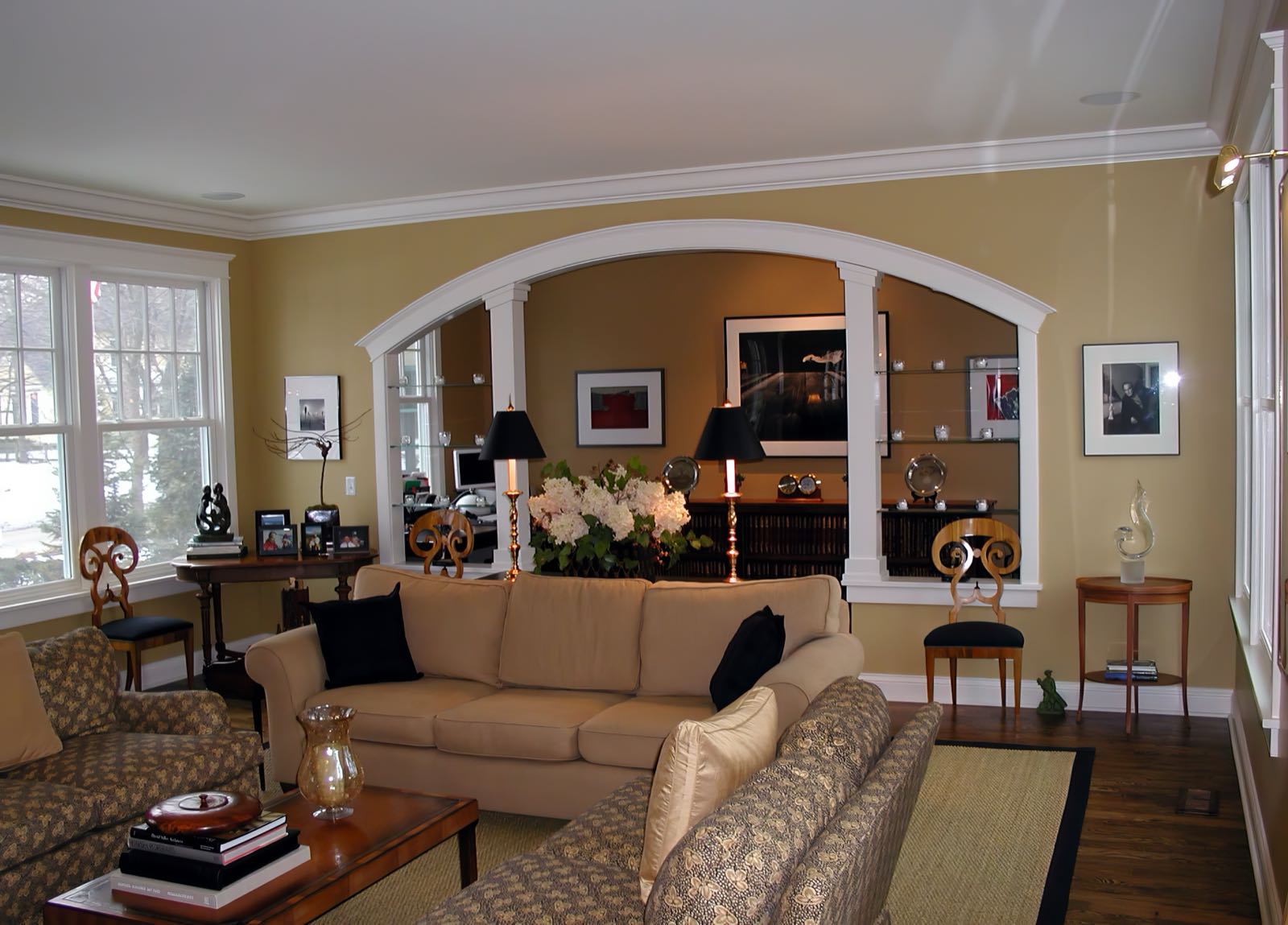 The living room from the other end, showing a wide arched opening with built-in cabinetry either side leading through to the next room.