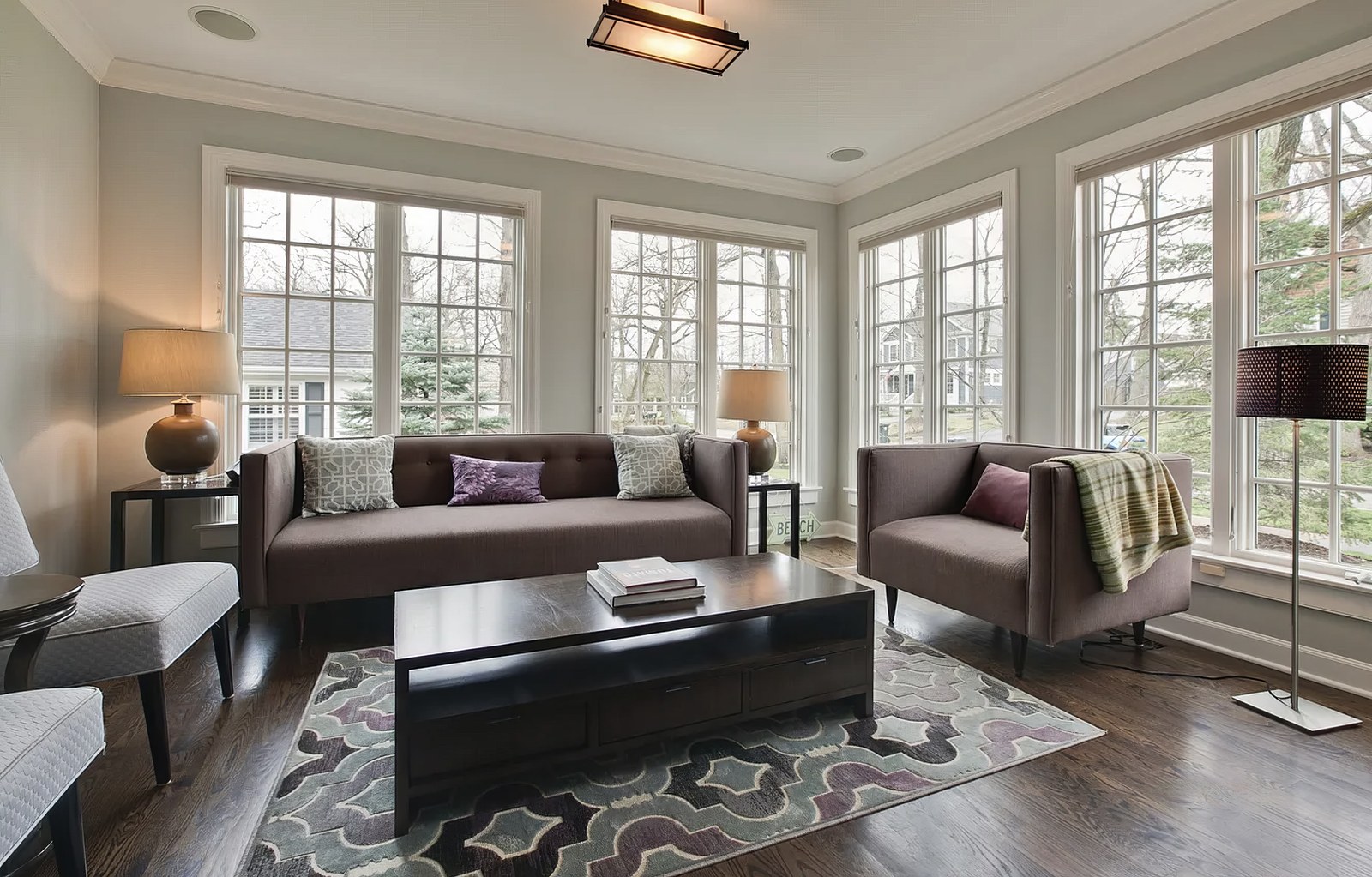 The sun room, glazed on three sides with divided-light windows from sill to head, looking out to the garden and the street.