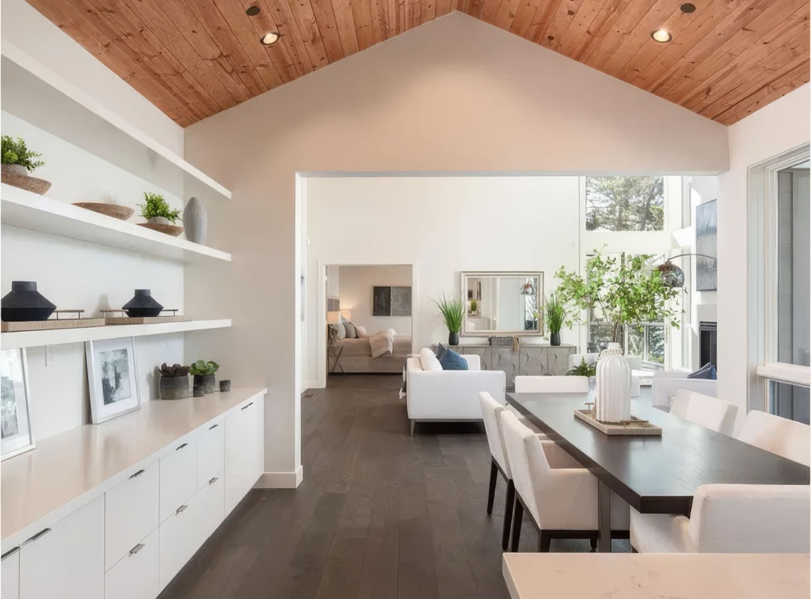 Dining area with a run of built-in shelving and low cabinets, opening through to the living room.