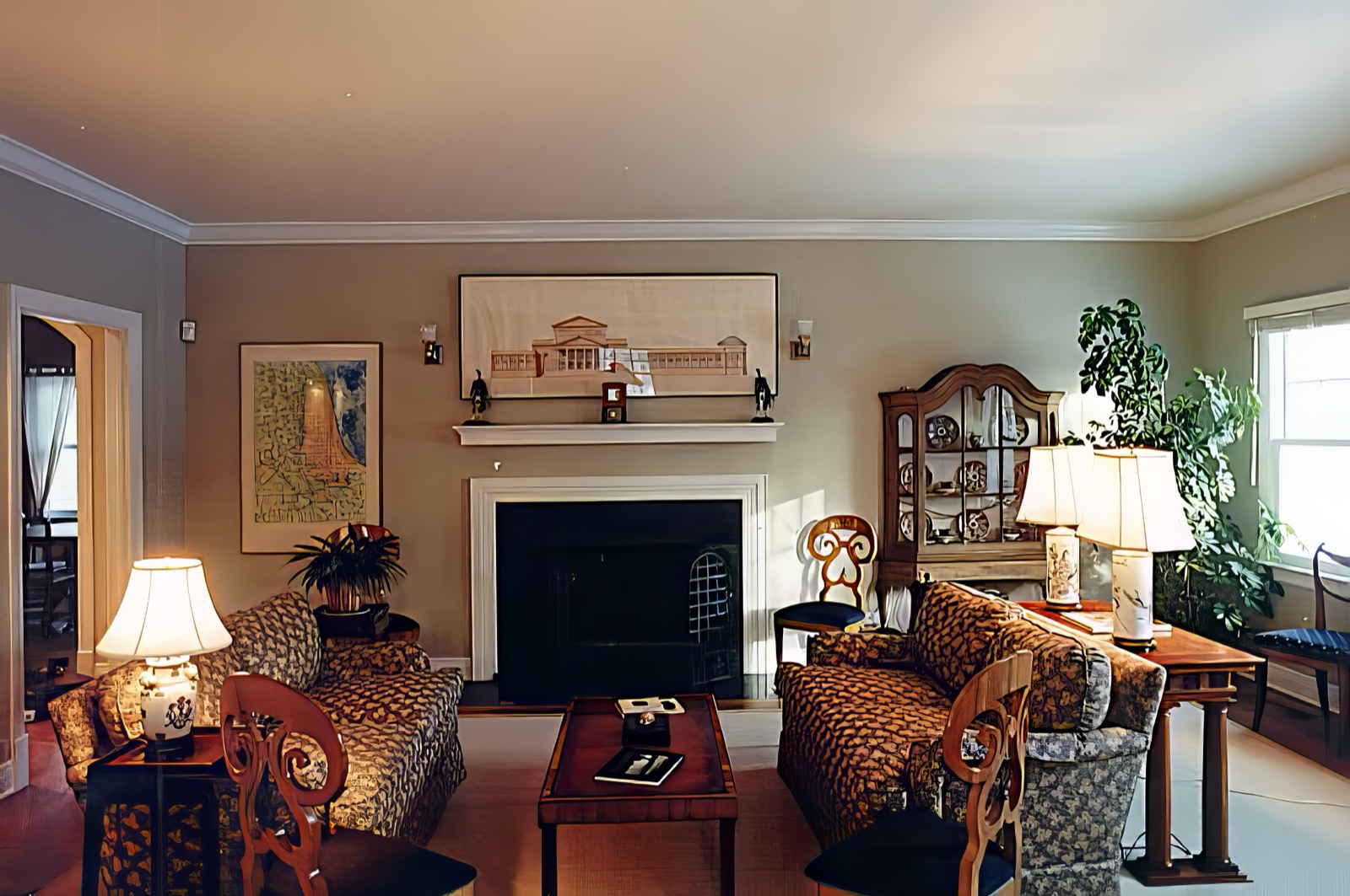 The living room, with a black-framed fireplace under a white mantel, a framed elevation drawing hung above it, a glazed cabinet to the right and a doorway through to the hall on the left.