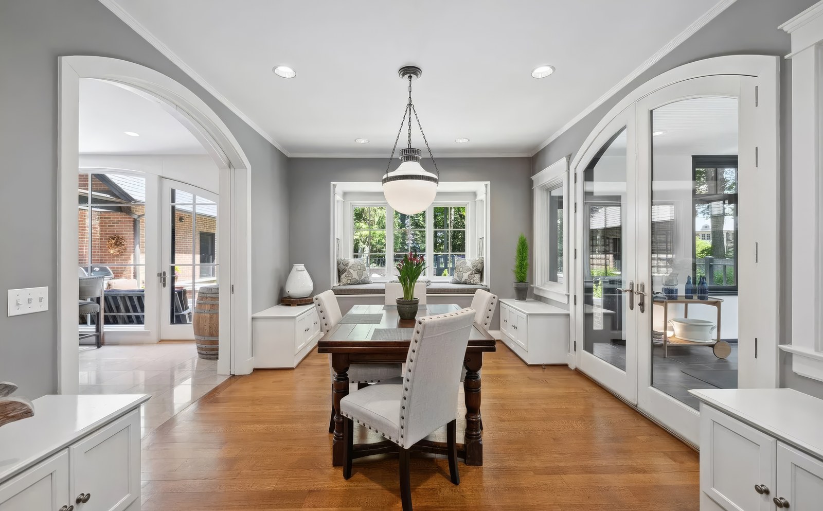 The breakfast area, with a window seat under a bay, a pendant over the table, and glazed doors out to the terrace on both sides.