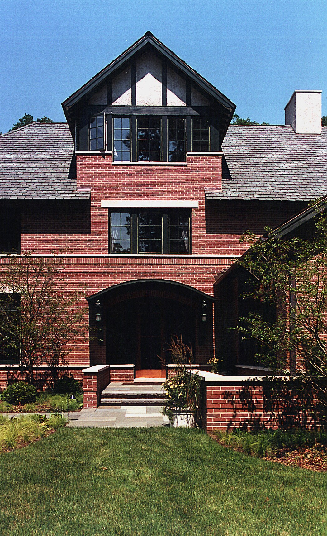 The entrance bay seen straight on: a deep brick arch over the door, a mullioned window above it, and a half-timbered gable at the top.