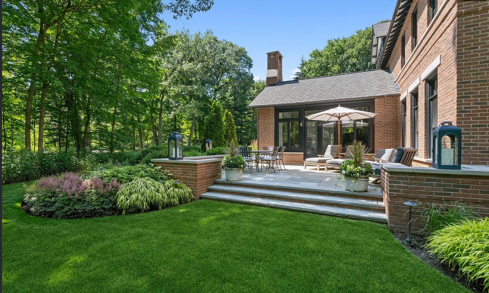 The south-west corner, with brick steps down from a raised terrace to the lawn and planting held in low brick walls.