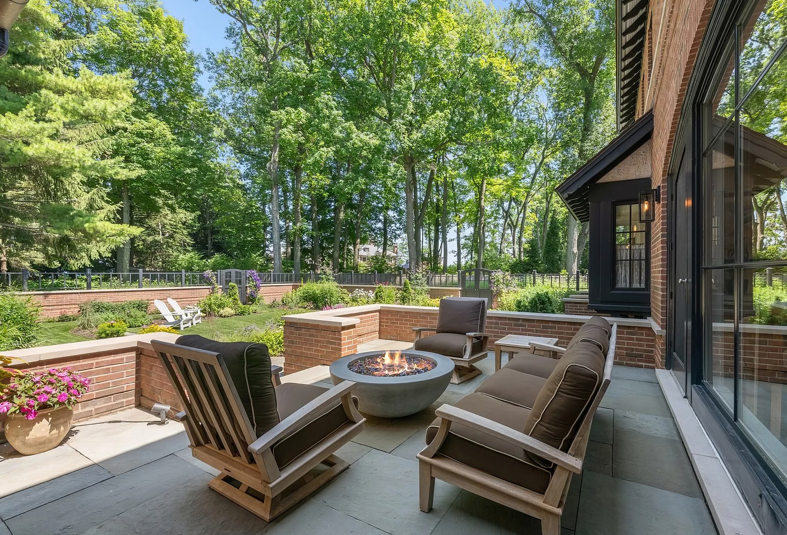 The terrace on the north-east side, with a fire bowl and low seating set against the brick parapet and the woods beyond.