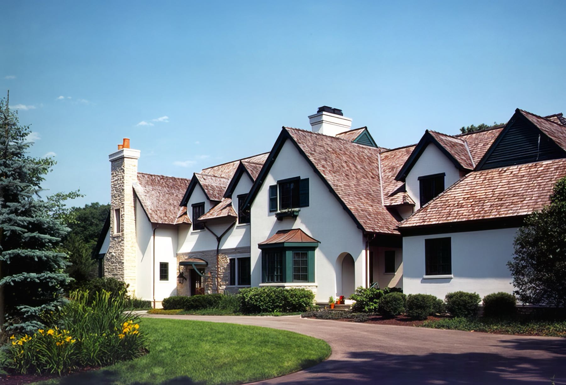 The house from the south-east, a traditional stone and slate elevation with tall chimneys and steeply pitched gables.