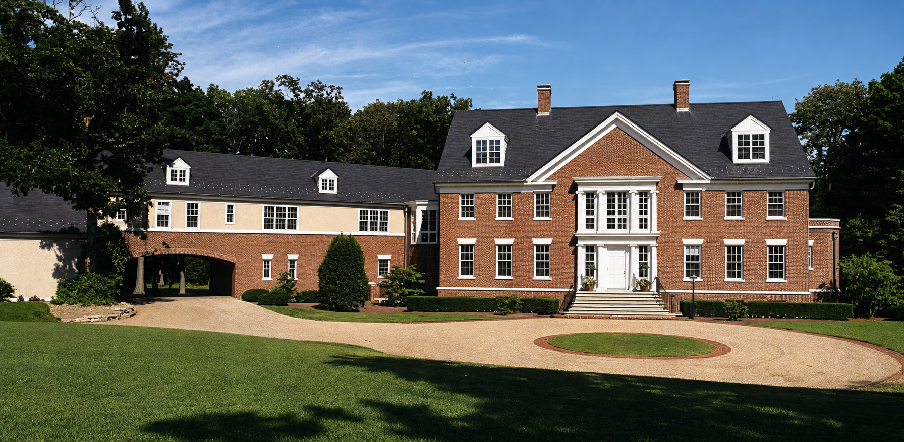 The house before the work: the same brick Georgian front, but with a flat pedimented centre bay and no portico, and a service wing to the left finished in stucco above a brick carriage arch, standing behind a gravel forecourt.