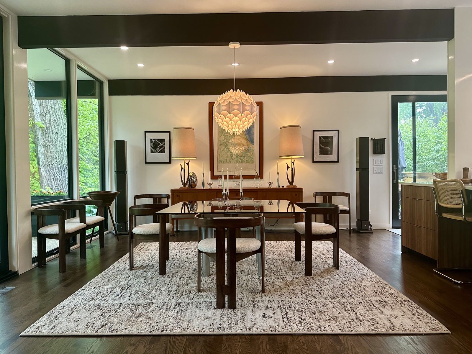 Dining area with a glass-topped table, pendant light and full-height glazing to the ravine on the left.