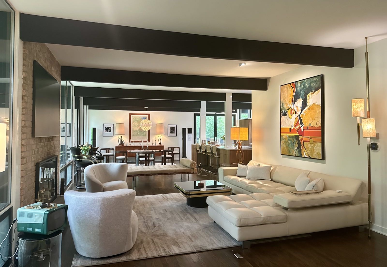 Living room with a brick fireplace, pale sectional sofa, and a long view back through the dining area to the kitchen.