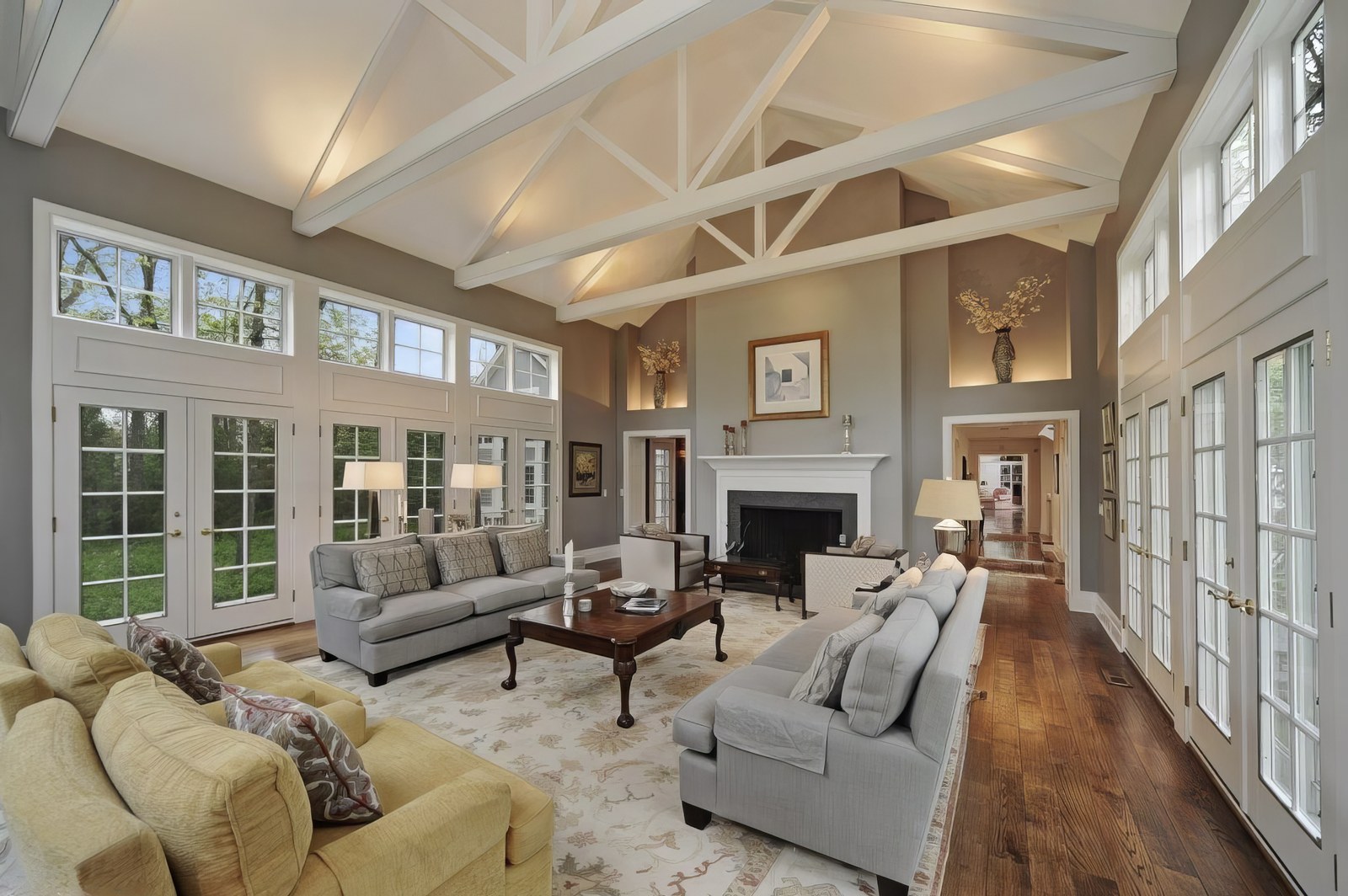 The living room from the other end, showing the fireplace with a white mantel between lit niches, and the trusses running the length of the vault.